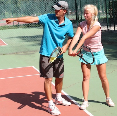 Une joueuse de tennis du stage de tennis adulte qui aprend le revers avec son enseignant de tennis